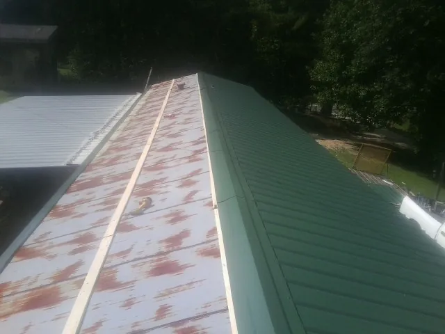 Old rusted panels beside newly installed green metal roofing — Wind Damage Roof Repair by Roofing Brothers in Sandston