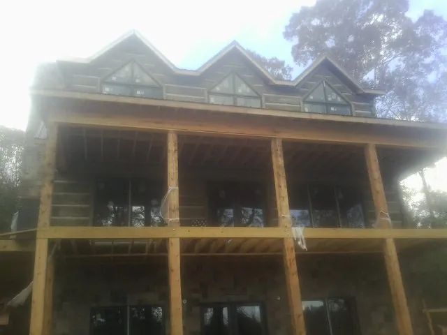 Dormers and porch framing on a large log home under construction — Roof Coating work by our crew in Sandston