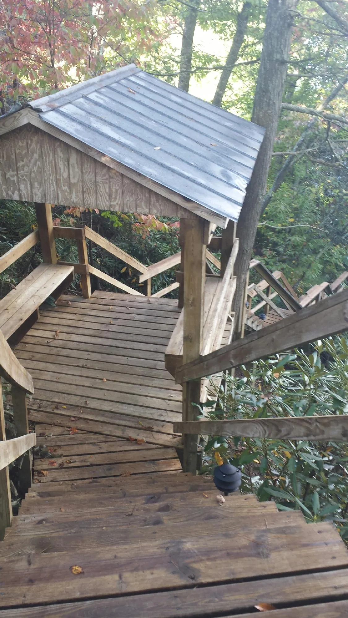 Metal roofed shelter over wooden steps on a wooded walkway — Skylight Repair & Installation work by our crew in Sandston