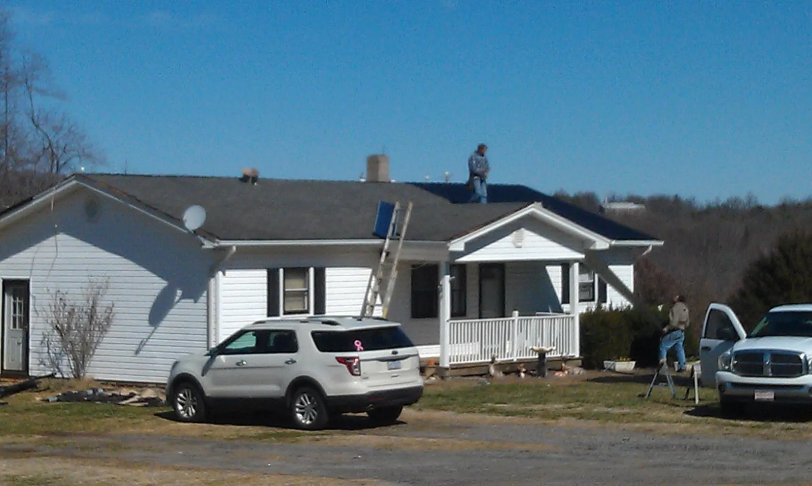 Roofers stripping shingles from a white ranch house roof in Sandston