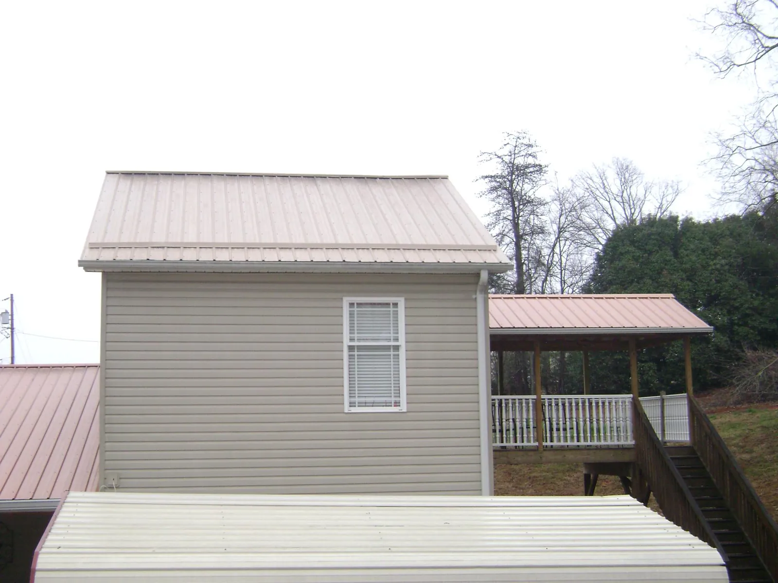 Tan metal roofs on a two story addition and attached porch, from a Roof Replacement job in Sandston